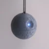 A Star Wars Death Star ornament with a twist mechanism that activates an LED light. Perfect for adding a galactic touch to your Christmas tree.